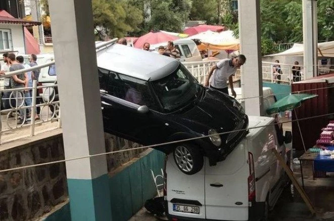 İzmir`de hakimiyetini kaybeden araç pazar yerinin üzerinde asılı kaldı